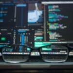 pexels-photo-577585-577585 Eyeglasses reflecting computer code on a monitor, ideal for technology and programming themes.